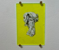 a yellow piece of art hanging on a wall